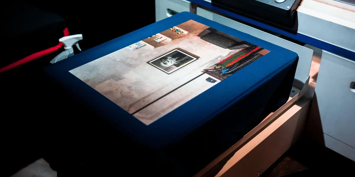 A direct-to-garment printer printing a full-color photograph onto a dark T-shirt